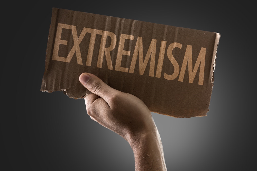 Extremism text on a bit of cardboard being held in raised hand