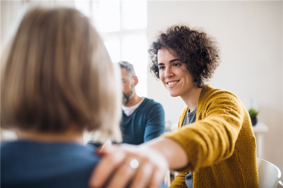 photo men and women sitting in a circle during group therapy supporting each other