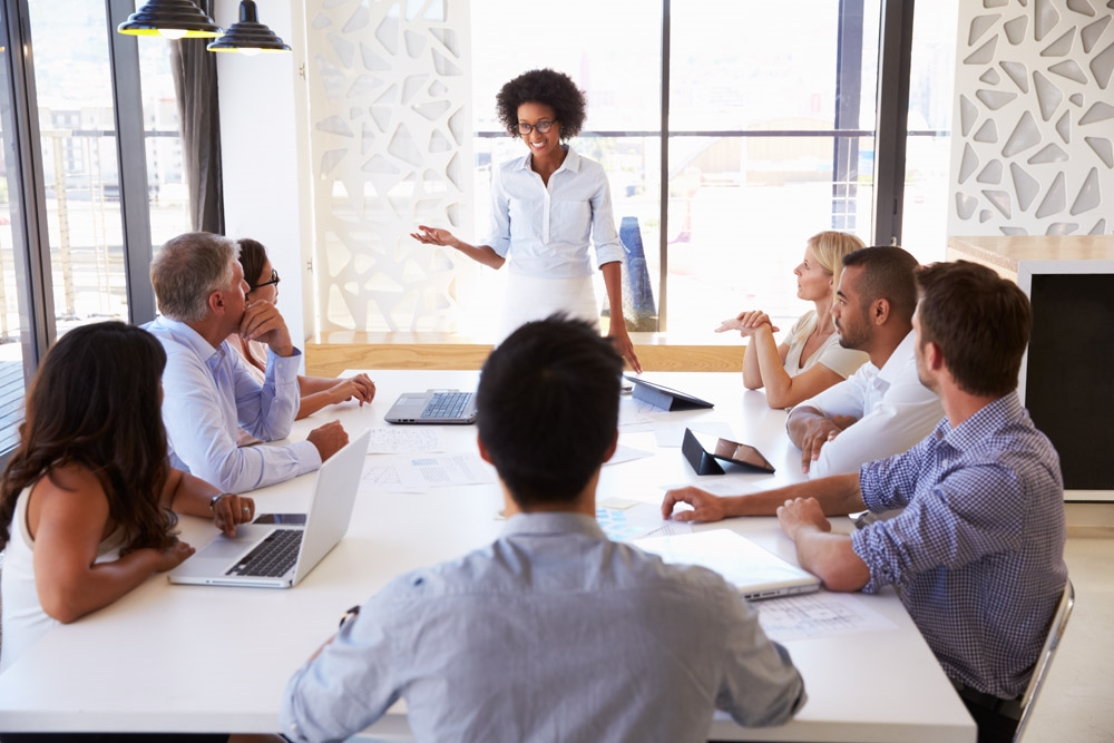 photo woman presenting to colleagues at a meeting